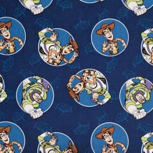 May include: A blue fabric with a repeating pattern of Toy Story characters, Woody and Buzz Lightyear, in white circles on a blue background.