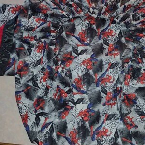 May include: A black and red baby blanket with a Spiderman pattern. The blanket has a soft, plush texture and is perfect for cuddling.