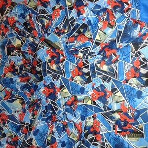 May include: A blue and red patterned fabric with a repeated image of Spiderman swinging through a city skyline.