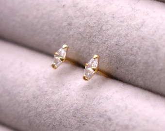 May include: A pair of gold earrings with small, clear, triangular-shaped stones.