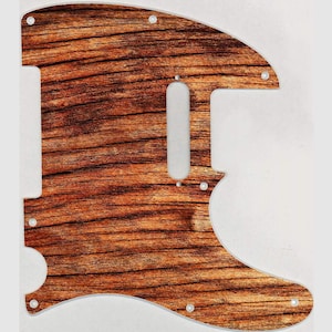 Könnte beinhalten: Ein braunes Holzmaserung-Gitarren-Pickguard mit einem Ausschnitt für einen Single-Coil-Tonabnehmer. Das Pickguard hat eine leicht abgerundete Form und ist aus einem strapazierfähigen Material gefertigt.
