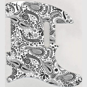 May include: Black and white paisley guitar pickguard. The pickguard is shaped like a guitar and has a paisley pattern.