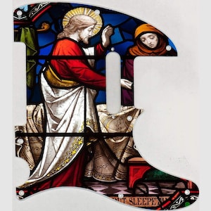 May include: A guitar pickguard with a stained-glass effect, showcasing a religious scene. The design includes a figure in red robes and a halo, alongside another in a brown hood. The pickguard has a white outline and screw holes.