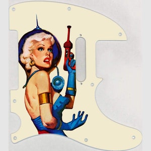 May include: A cream-coloured guitar pickguard featuring a vintage illustration of a woman in a blue and white space suit holding a red ray gun.