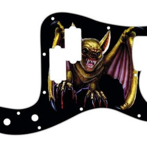 May include: Black guitar pickguard with a graphic of a yellow bat with red eyes and claws on a black background.
