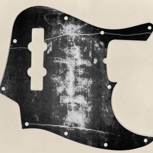 Może przedstawiać: Czarno-biały pickguard do gitary o postarzanym, zużytym wyglądzie. Pickguard ma duży wycięcie na pokrętła sterujące gitary i mniejsze wycięcie na przetwornik.