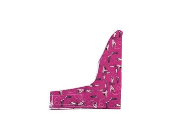 May include: A magenta fabric cover with a repeating pattern of ballerinas in black and white outfits, featuring white swirling lines. The item has an L-shaped silhouette with visible white stitching along the bottom and side edges.