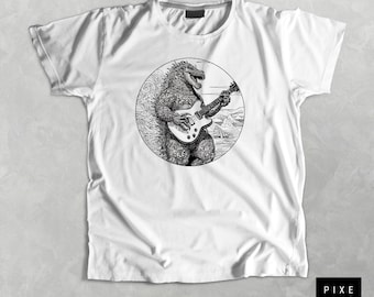 May include: A white t-shirt with a black and white illustration of a monster playing a guitar. The monster is surrounded by waves and a mountain in the background.