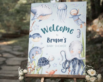 May include: Welcome to Bruna's Baby Shower sign with a blue and white watercolour design featuring a whale, jellyfish, octopus, turtle, and a scuba diver.
