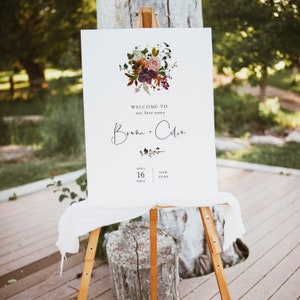 May include: A white wedding welcome sign with a floral illustration and the text "Welcome to our love story,  Brianna + Colin, April 16, 2022, New York".