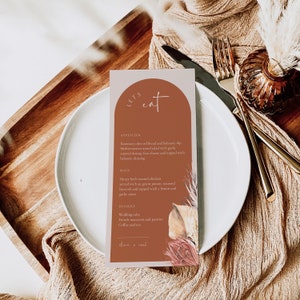 Può includere: Un menu di nozze con un tema rustico. Il menu è stampato su una carta marrone con un arco bianco e le parole "Let's Eat" in scrittura bianca. Il menu include opzioni di antipasti, piatti principali e dessert.