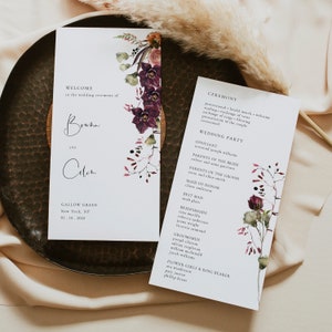 May include: Wedding ceremony program with a watercolor floral design in shades of burgundy and pink. The program includes the names of the bride and groom, "Braha and Colin", the officiant, wedding party, and ceremony details.