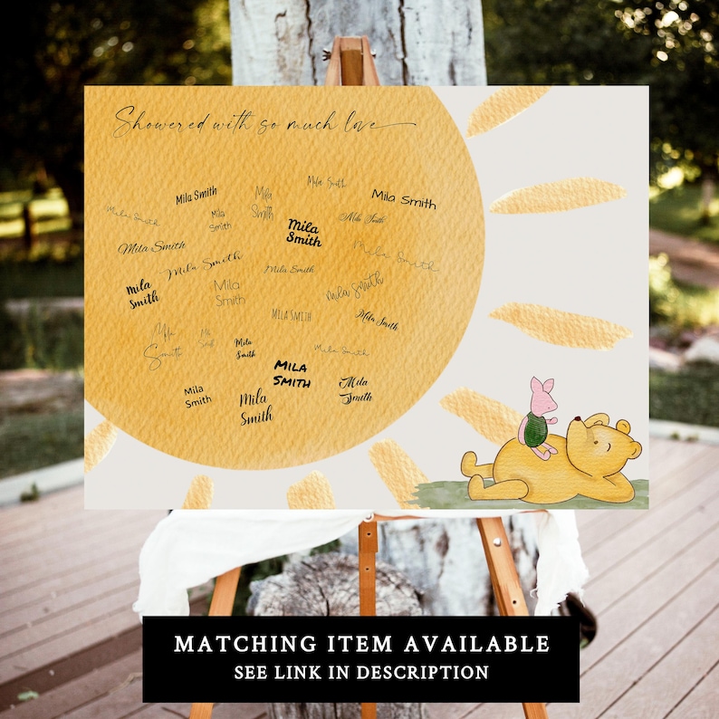 May include: A yellow sun with a watercolor effect and a Winnie the Pooh character with Piglet on his back. The sun has a circle in the middle with the words "Showered with so much love" and many signatures around the circle.