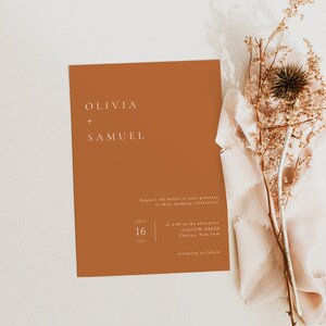 Puede incluir: Una invitaci&oacute;n de boda de color &oacute;xido con texto blanco. La invitaci&oacute;n dice "Olivia + Samuel" e incluye la fecha "16 de abril de 2022" y la hora y el lugar de la ceremonia de boda.