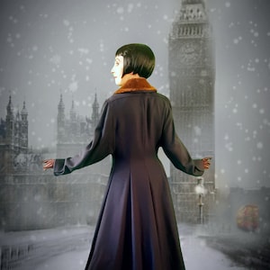 May include: A woman in a long, dark blue coat with a brown fur collar stands in front of Big Ben in London. The woman is wearing brown shoes and has short, dark hair. Snow is falling in the background.