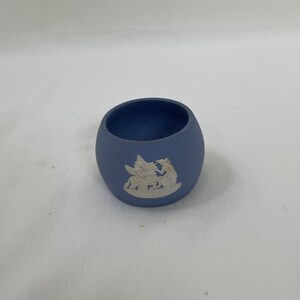 May include: A small, light blue ceramic trinket dish with a white raised design of a couple of fairies.