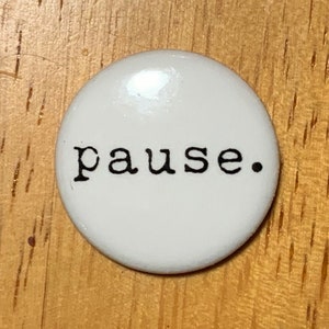 May include: White round button with the word "pause." printed in black.
