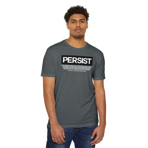May include: A dark gray t-shirt with a black rectangle and the word "PERSIST" in white letters. The text below the rectangle reads "If you persist, remarkable things will happen. When we look back, we realize that the only good things that have ever happened to us were the things we fought hard for. Better than anything we could have ever imagined. Who will you be in the realm of street equity?"