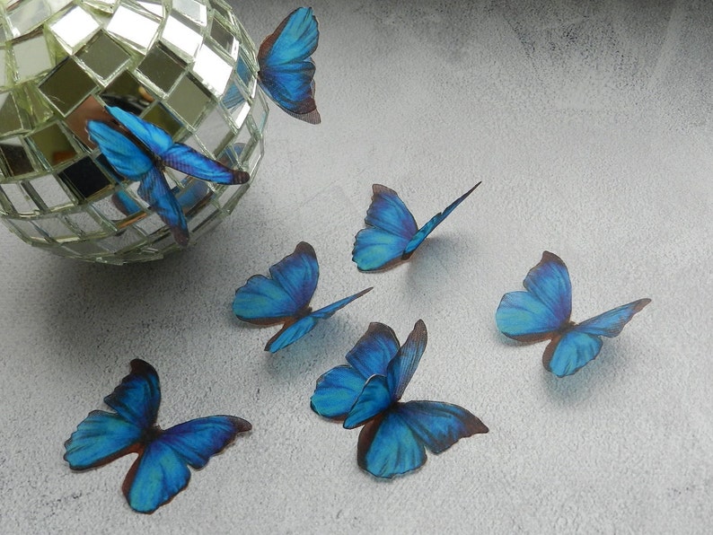 May include: Six blue butterfly decorations with a mirrored disco ball in the background.