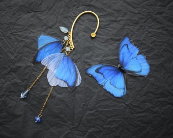 May include: A gold ear cuff with a blue butterfly charm and dangling blue crystal beads.