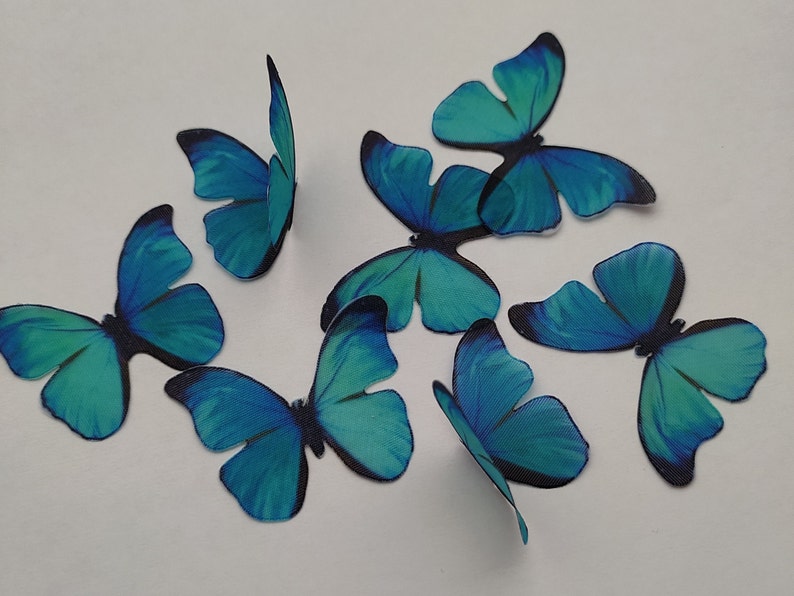 May include: Eight teal blue butterfly cake toppers. The butterflies have black markings and are made of edible wafer paper.