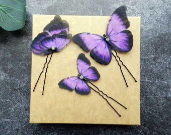 May include: Three purple butterfly hair clips with black bobby pins. Each butterfly has a rhinestone in the center.