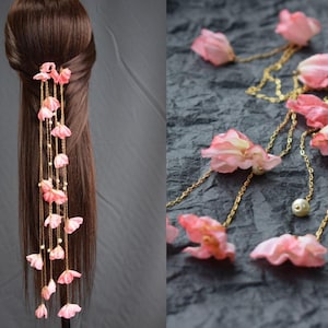 May include: A hair accessory featuring pink flower petals and small pearls strung on gold-colored chains. The accessory is shown in the hair and also displayed separately. The petals are a soft pink color.