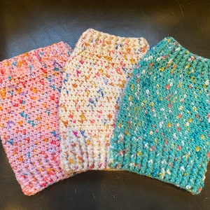 May include: Three crocheted hats in pink, white, and teal with colorful flecks throughout.