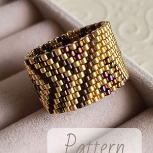 May include: A wide, beaded ring with a geometric pattern. The ring is made of small, gold-colored beads with hints of brown and purple. The word "Pattern" is printed on a white label.