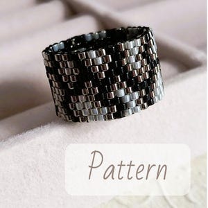 Könnte beinhalten: Ein Perlenring mit geometrischem Muster. Der Ring ist hauptsächlich schwarz, silber und weiß, mit einem sich wiederholenden Design. Das Wort "Pattern" wird in einer weichen, kursiven Schrift auf einem weißen Rechteck angezeigt.