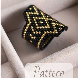 May include: A wide beaded ring featuring a geometric design in black and gold. The ring is shown in close-up. The word "Pattern" is displayed on a white label in the image.