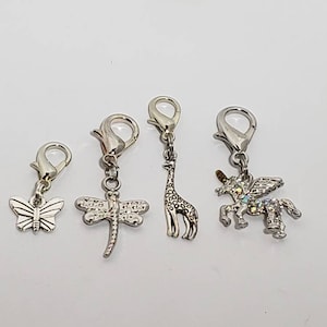 May include: Four silver charm clips with different animal designs. The charms include a butterfly, dragonfly, giraffe, and unicorn.