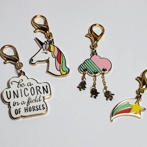 May include: Four gold-tone charms with a unicorn, a cloud with raindrops, a star, and a cloud with the text "Be a unicorn in a field of horses".