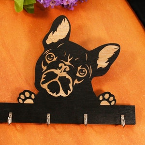 May include: Black wooden key holder shaped like a French bulldog with four hooks. The bulldog is looking up with its tongue out.