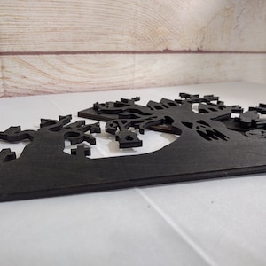May include: Black wooden Halloween decoration with a spooky silhouette of a haunted house, trees, and a graveyard.