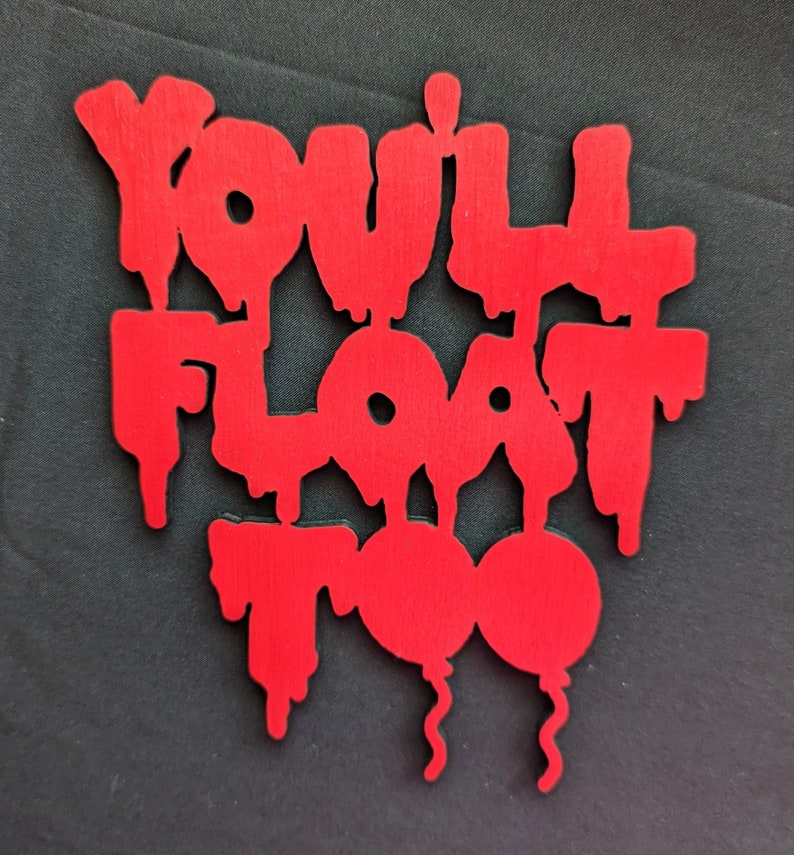 May include: A red wooden sign with the phrase "YOU'LL FLOAT TOO" in a dripping font. Two red balloons are at the bottom of the sign. The sign is on a black background.
