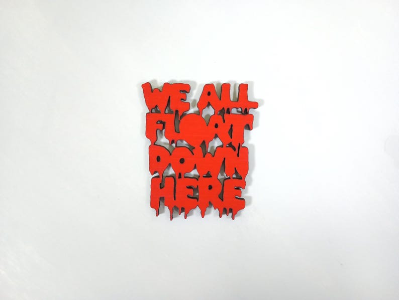 May include: Red wooden sign with the phrase "WE ALL FLOAT DOWN HERE" in a dripping font. The sign is square and has a white background.