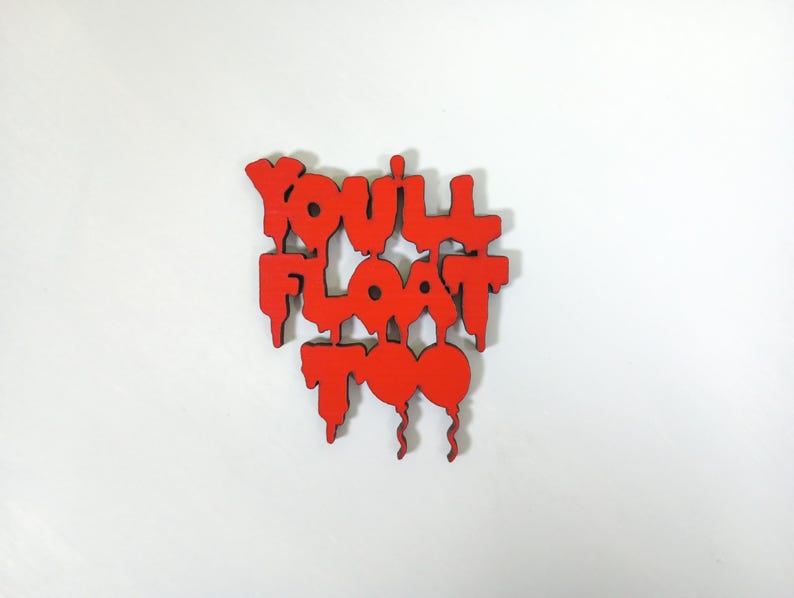 May include: A red wooden sign with the phrase "YOU'LL FLOAT TOO" in a dripping, stylized font. The sign has a white background and features a balloon design.
