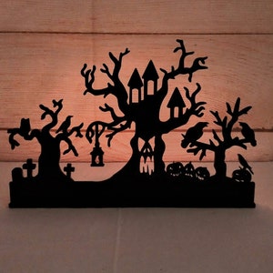 May include: Black silhouette of a haunted house with a tree, crows, and a graveyard. The house has windows and a door. The tree has branches and leaves. The crows are perched on the branches. The graveyard has tombstones and a lantern.
