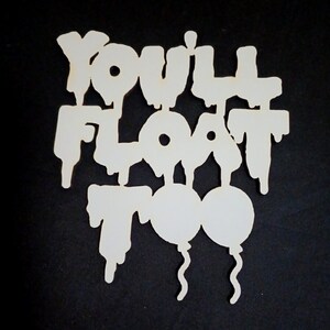 May include: White wooden cutout with the words "YOU'LL FLOAT TOO" in a dripping font, with two balloon shapes below. The cutout is set against a black background.