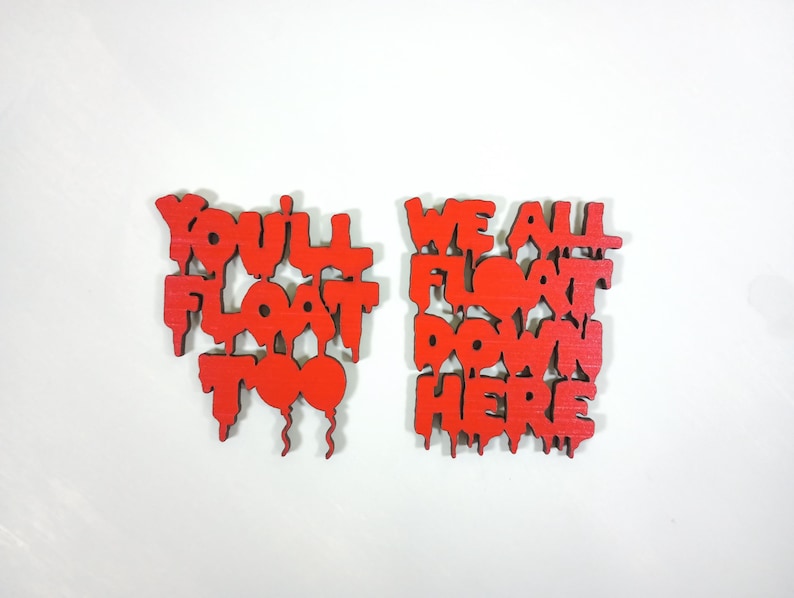 May include: Two red wooden signs with the phrases "YOU'LL FLOAT TOO" and "WE ALL FLOAT DOWN HERE" in a dripping font. The signs are on a white background.