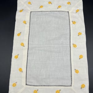 May include: White linen table runner with a yellow embroidered pineapple design around the border.