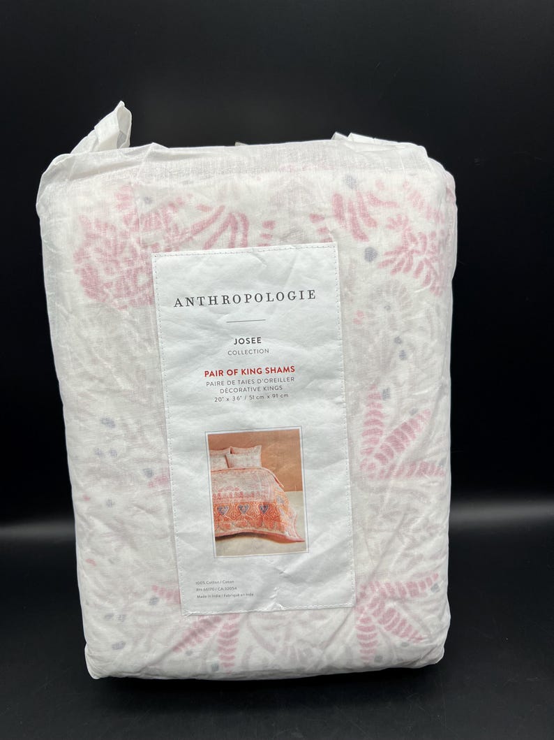 May include: A package of Anthropologie Josee Collection King Shams. The white fabric is patterned with pink and gray floral designs. The label reads "Pair of King Shams" and shows a picture of the shams.
