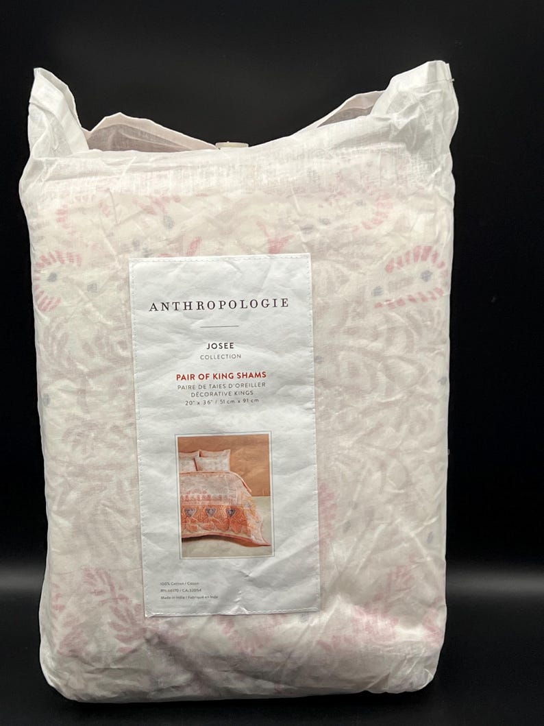May include: A package of king shams from the Anthropolgie Josee Collection. The shams are in a white package with a floral pattern in pink and red. The label reads "Pair of King Shams" and "20 x 36 in / 51 cm x 91 cm."
