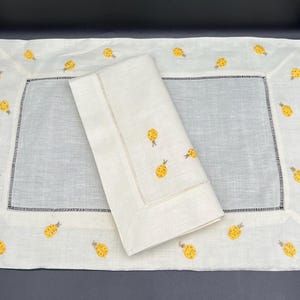 May include: A white linen table runner with a white linen napkin. Both are embroidered with yellow pineapple designs.