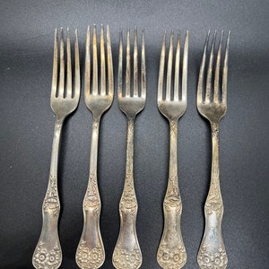 May include: Set of five silver forks with ornate handles. Each fork has a different initial engraved on the handle.