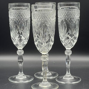 May include: Set of four clear glass champagne flutes with a cut crystal design. The flutes have a tall, slender stem and a round base.