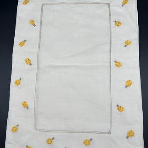 May include: A white linen tablecloth with a yellow pineapple embroidered border.