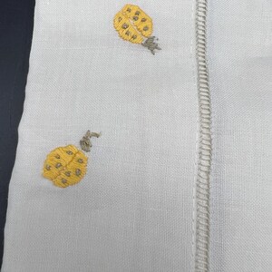 May include: White linen fabric with two embroidered yellow ladybugs with brown accents.