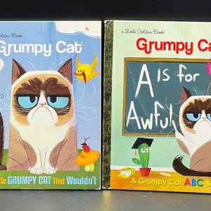 May include: Two "Grumpy Cat" Little Golden Books. One book cover features Grumpy Cat with a butterfly and the text "The Little GRUMPY CAT That Wouldn't". The other book cover has Grumpy Cat with the text "A is for Awful".